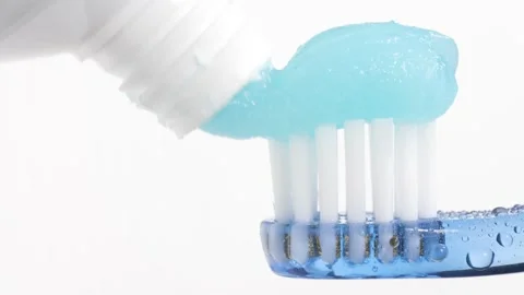 Toothbrush and toothpaste. Macro view of blue toothbrush on which blue Stock Footage 159133334