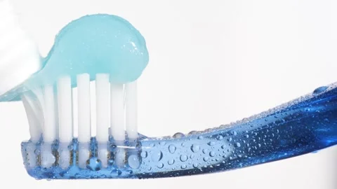 Toothbrush and toothpaste. Macro view of blue toothbrush on which blue Stock Footage 159133513