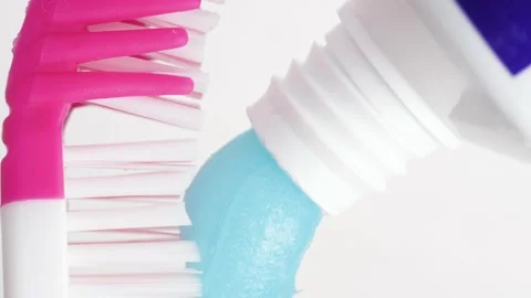 Toothbrush and toothpaste. Vertical macro view of pink toothbrush on which blue Stock Footage 159133178