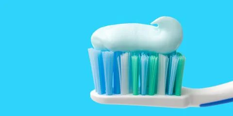 Toothbrush head with toothpaste on blue background, close-up view, macro Stock-Fotos