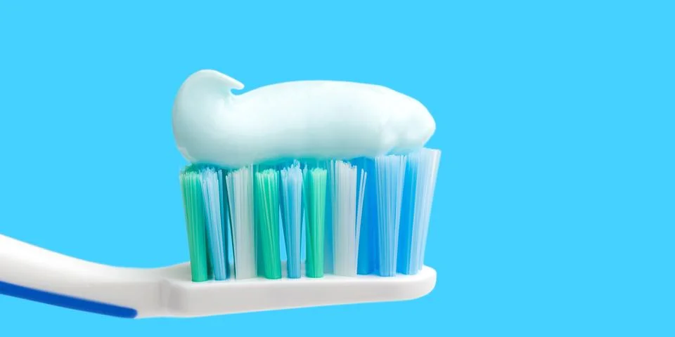 Toothbrush head with toothpaste on blue background, close-up view, macro Foto stock