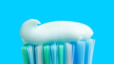 Toothbrush head with toothpaste on blue background, close-up view, macro Stock Photos