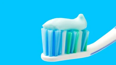 Toothbrush head with toothpaste on blue background, close-up view, macro Stock Photos