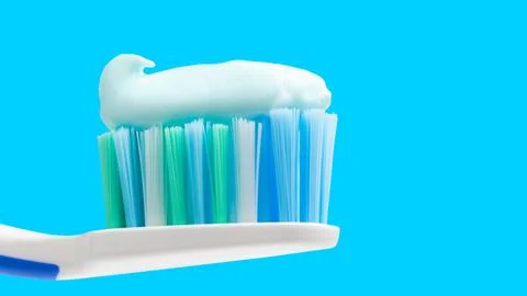 Toothbrush head with toothpaste on blue background, close-up view, macro Foto stock