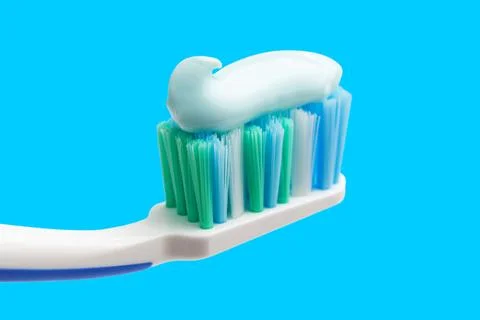 Toothbrush head with toothpaste on blue background, close-up view, macro Stock Photos