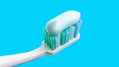 Toothbrush head with toothpaste on blue background, close-up view, macro Stock Photos