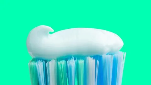 Toothbrush head with toothpaste on mint green background, close-up view, macr Stock Photos