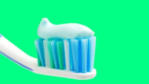 Toothbrush head with toothpaste on mint green background, close-up view, macr Stock Photos