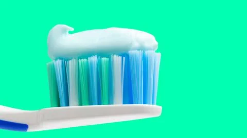 Toothbrush head with toothpaste on mint green background, close-up view, macr Stock Photos