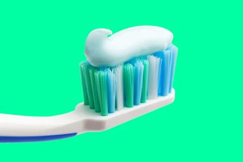Toothbrush head with toothpaste on mint green background, close-up view, macr Stock Photos