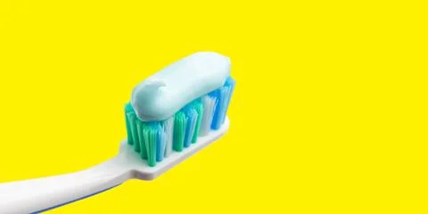Toothbrush head with toothpaste on yellow background, close-up view, macro Stock Photos