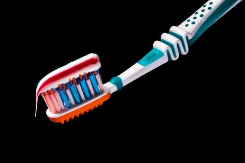 Toothbrush with multicolored toothpaste on it isolated on black background Stock Photos