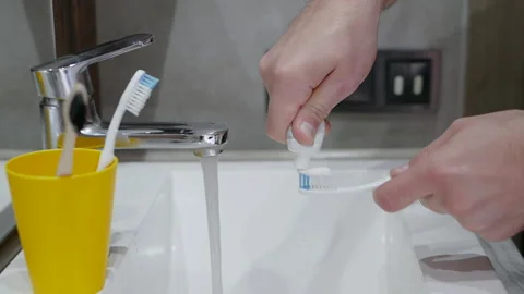 Toothbrush Squeeze toothpaste onto a toothbrush over a sink. Dental care Stock Footage 212618300