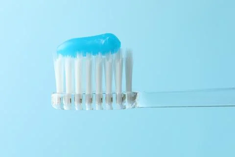 Toothbrush with toothpaste in air on light blue background, closeup Stock Photos