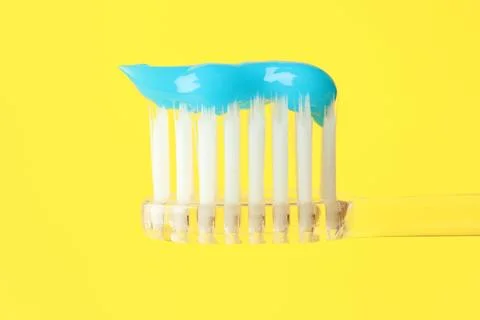 Toothbrush with toothpaste in air on yellow background, closeup Stock Photos
