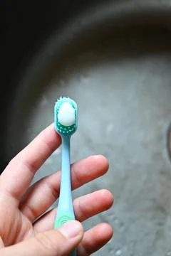 A toothbrush with toothpaste  is being held by someone Stock Photos