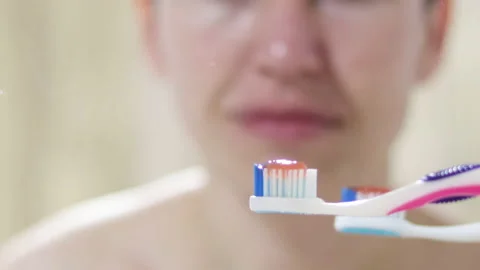 Toothbrush with toothpaste in front of a smiling woman or girl. Vídeo Stock 189926060