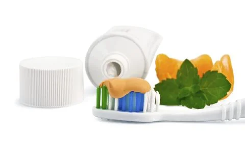 Toothbrush with toothpaste orange, a sprig of green mint, orange slices, a tube Stock Photos