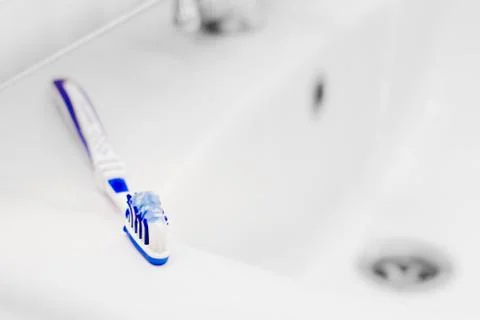 Toothbrush with toothpaste on washbasin. Small depth. Stock Photos