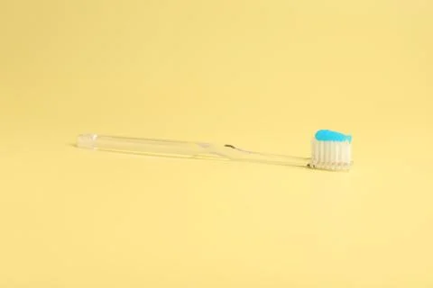Toothbrush with toothpaste on yellow background, closeup Stock Photos
