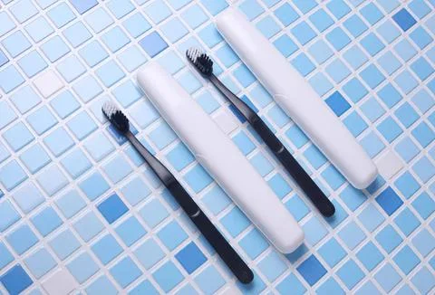 Toothbrushes and toothpaste on bathroom tiled wall Fotos Stock