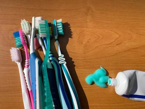 Toothbrushes and Toothpaste on Wooden Surface Stock Photos