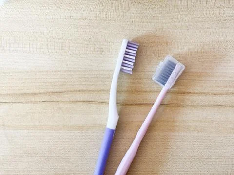 Toothbrushes With And Without Protective Cap On Wooden Background Stock Photos