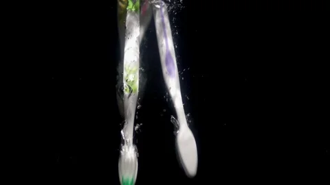 Toothbrushes fall into the water on a black background. Stock Footage 128740857