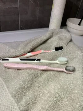 Toothbrushes lying on towel, three different toothbrushes rest on soft gray  Stock Photos