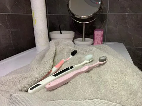 Toothbrushes lying on towel, three different toothbrushes rest on soft gray  Stock Photos