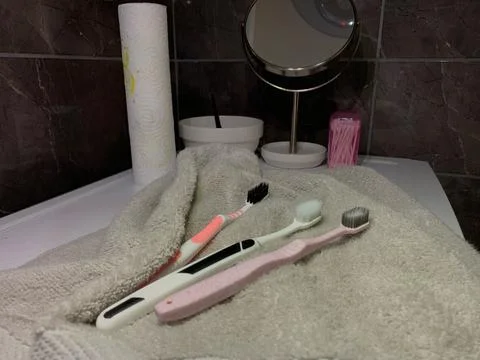 Toothbrushes lying on towel, three different toothbrushes rest on soft gray  Stock Photos