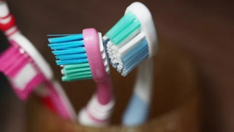 Toothbrushes stored in a container on a wooden surface Stock Footage 305438237