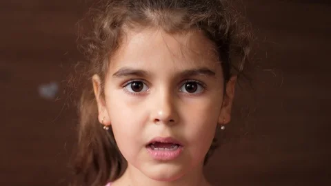 Toothless girl eats chocolate candy. A child without front teeth bites off candy Stock Footage 118838767