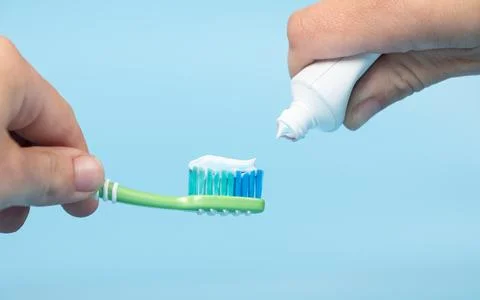 Toothpaste is applied to the toothbrush,tooth brushing in hand on blue back.. 스톡 사진