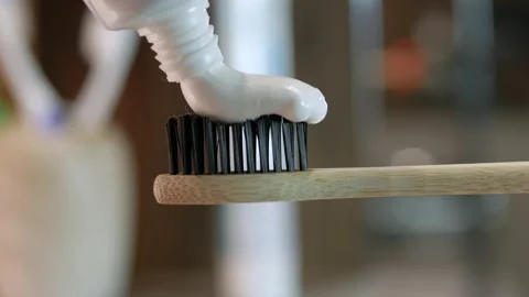 Toothpaste is applied to a wooden eco toothbrush. Squeeze toothpaste Stock Footage 212045647