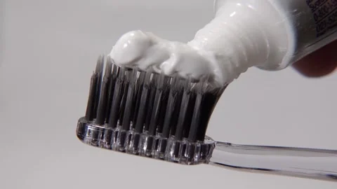 Toothpaste being applied to a black toothbrush against. Stock Footage 313988070