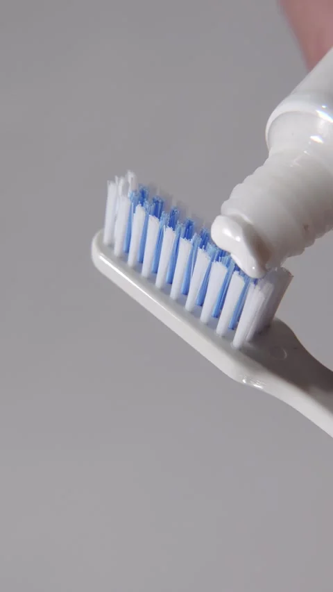 Toothpaste being smoothly applied to the bristles of a toothbrush Stock Footage 313985715