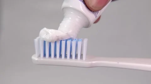 Toothpaste being smoothly applied to the bristles of a toothbrush in a clean. Stock Footage 313985908