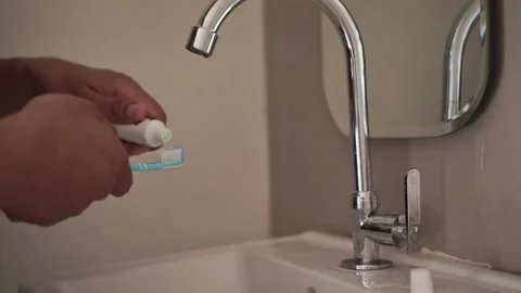 Toothpaste being squeezed onto a toothbrush by hand on the wastafel. Vídeos de archivo 337723824