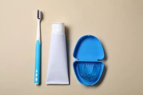 Toothpaste, brush and container with dental mouth guard on beige background.. Stock Photos