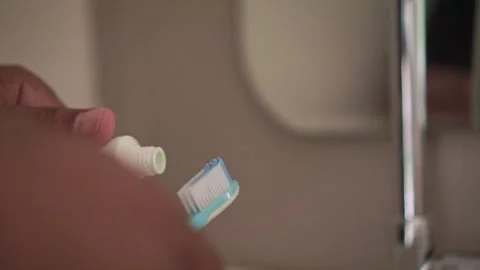 Toothpaste dispensed onto toothbrush bristles in a bathroom. Vídeos de archivo 337723770