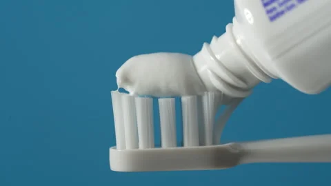 Toothpaste squeezed on the white toothbrush on blue background,, close up Stock Footage 303379731