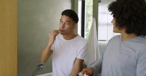 Toothpaste squeezing causing diverse male friends brushing teeth at bathroom Stock Footage 311026050