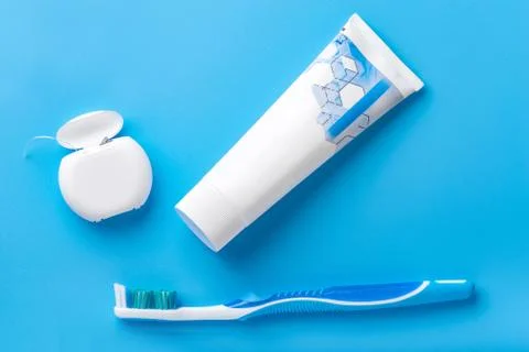 Toothpaste, toothbrush, and dental floss lie on a blue background. Top view o Stock Photos