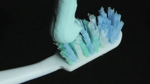 Toothpaste on a toothbrush closeup, Black background, Macro Video stock 61246398