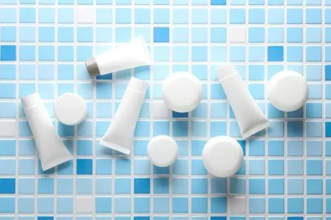 Toothpaste tubes and caps on blue mosaic tile background Fotos Stock