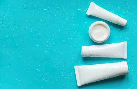 Toothpaste tubes and open container on blue background Stock Photos
