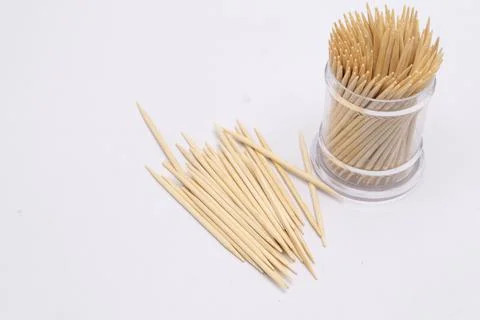 Toothpicks in a Clear Plastic Container and Scattered on a White Surface, C.. Stock Photos