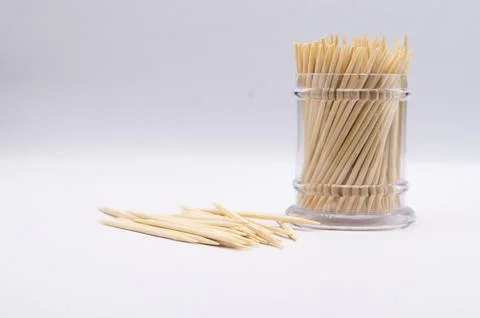 Toothpicks in a Clear Plastic Container with Scattered Toothpicks on a Whit.. Stock Photos