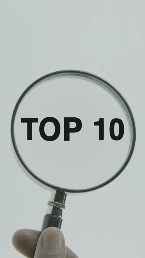 Top 10 text or word highlighted by a magnifying glass in a hand on a white Stock Footage 303525142